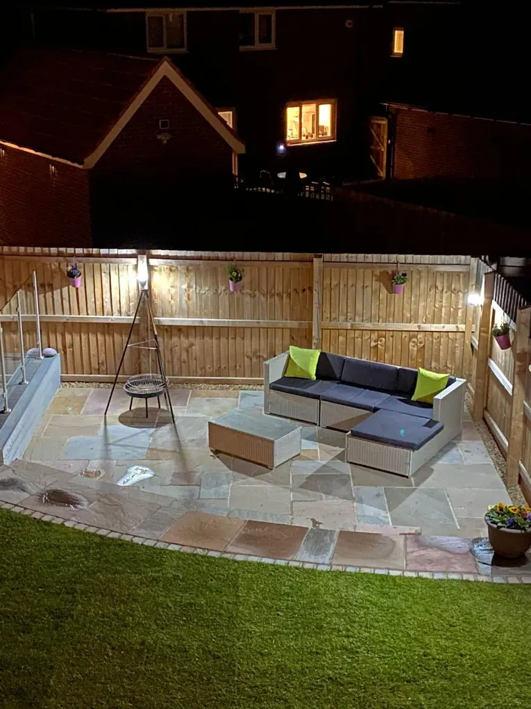 Evening garden patio with rattan corner sofa and festoon lighting, completed in Leeds by CLM Projects