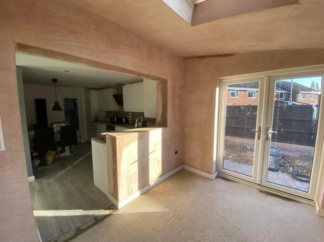 Plastered extension interior opening into a kitchen