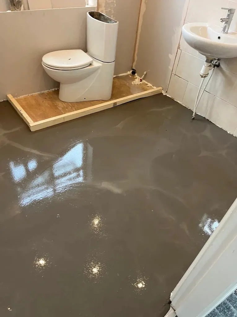 Self-levelling screed floor laid around a new toilet