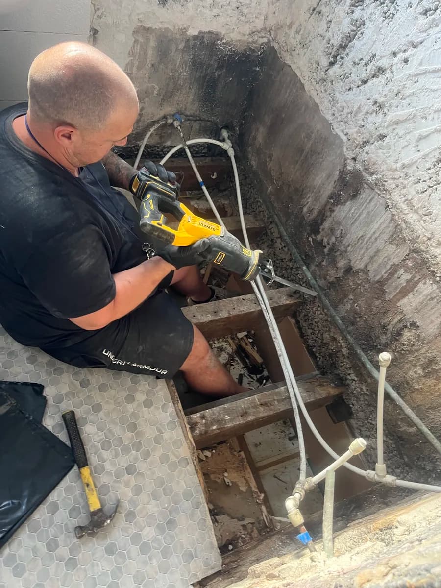 Darren from CLM Projects cutting out rotten floor timbers during a bathroom floor repair in Leeds