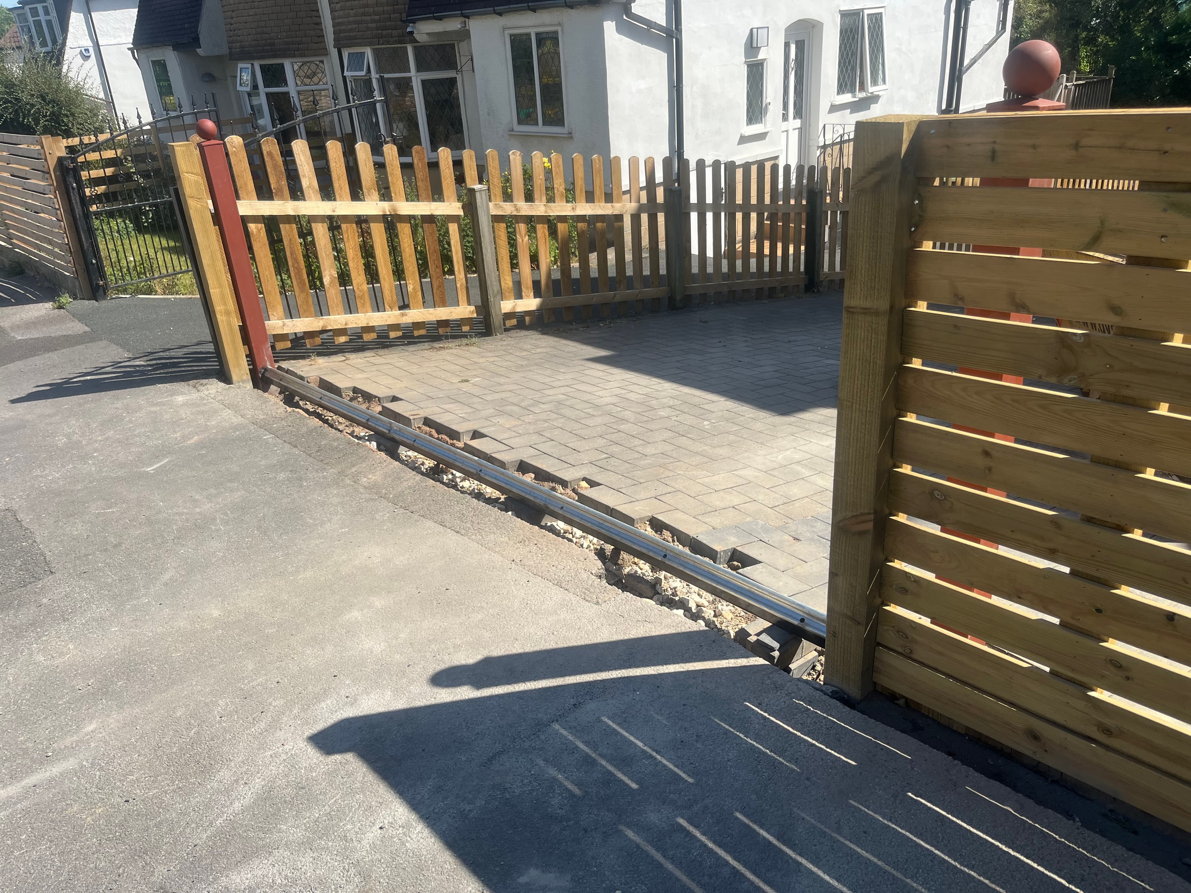 Bespoke sliding timber gate running on a ground track at the entrance to a block paved driveway in Leeds